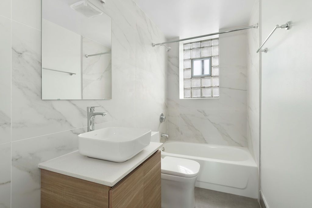 A bathroom with a sink , toilet , tub and mirror.
