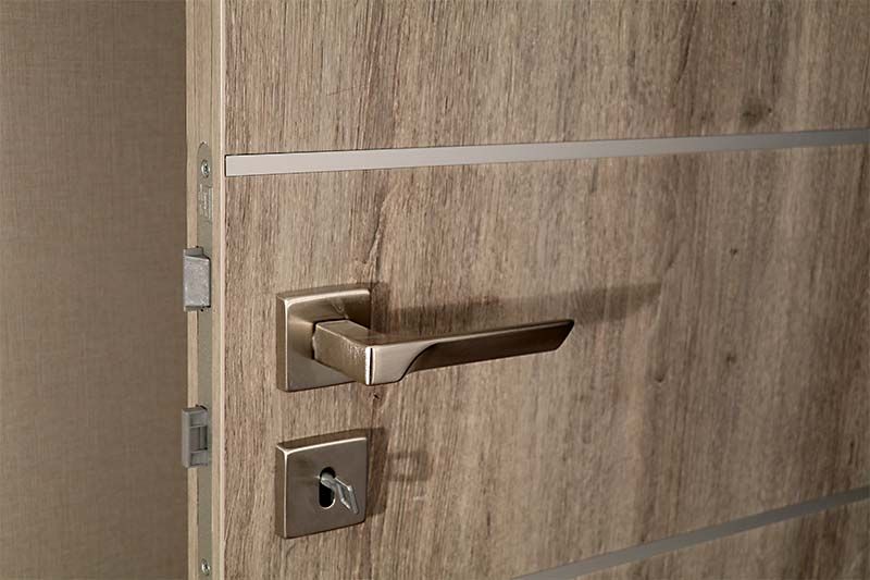 A close up of a wooden door with a metal handle and a key.