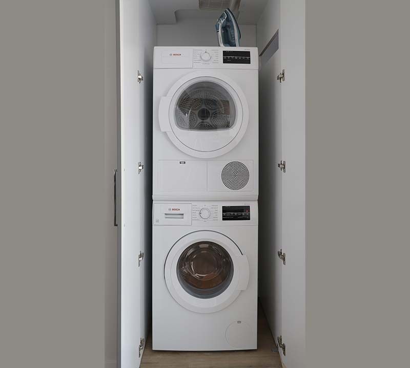 A washer and dryer are stacked on top of each other in a closet.