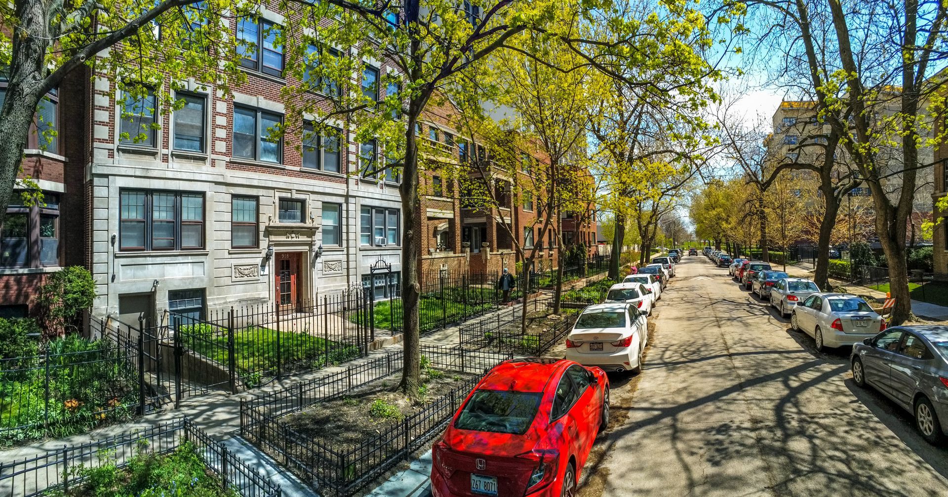 A red car is parked on the side of a residential street.