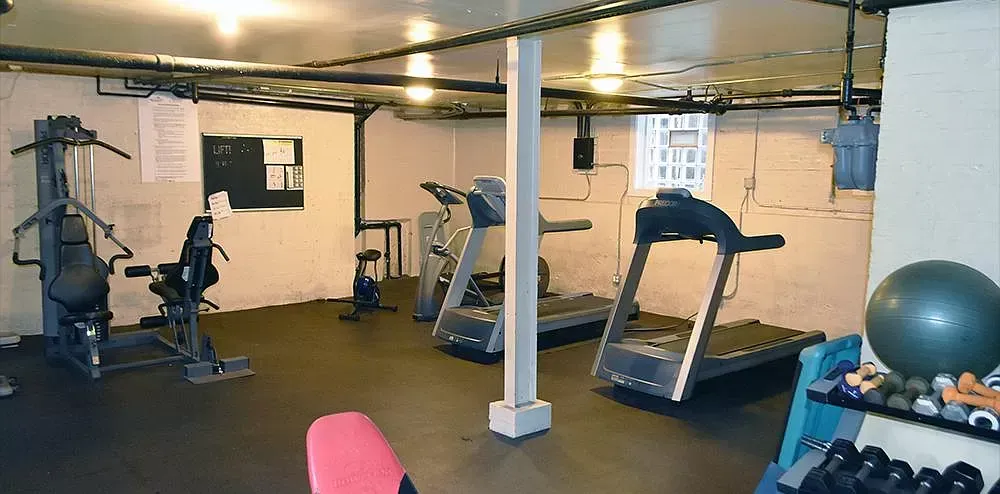 A gym with treadmills , exercise bikes and a dumbbell rack