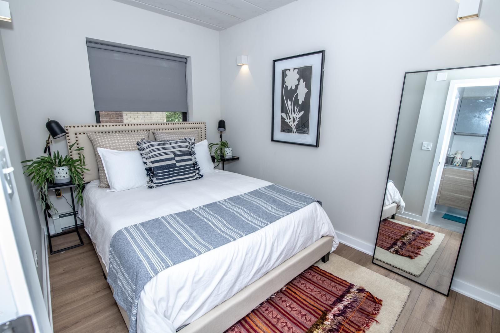 A bedroom with a bed , mirror and rug.