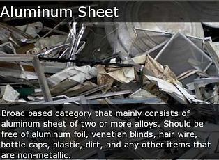 Piled scrap aluminum sheets and bent metal pieces in a recycling bin, labeled