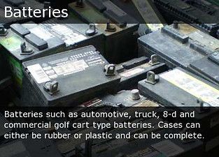Close-up of black automotive batteries with metal terminals and warning labels in a storage area