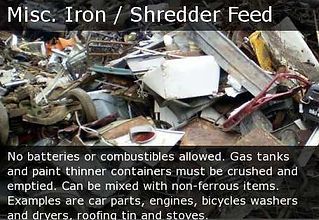 Scrap metal pile labeled “Misc. Iron / Shredder Feed” with safety notes about no batteries or combustibles