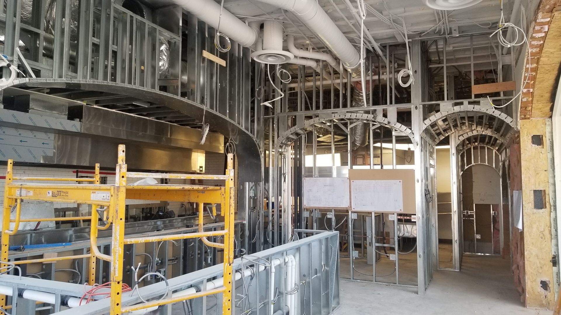 Interior of a building under construction, with scaffolding, exposed framing, and unfinished walls.