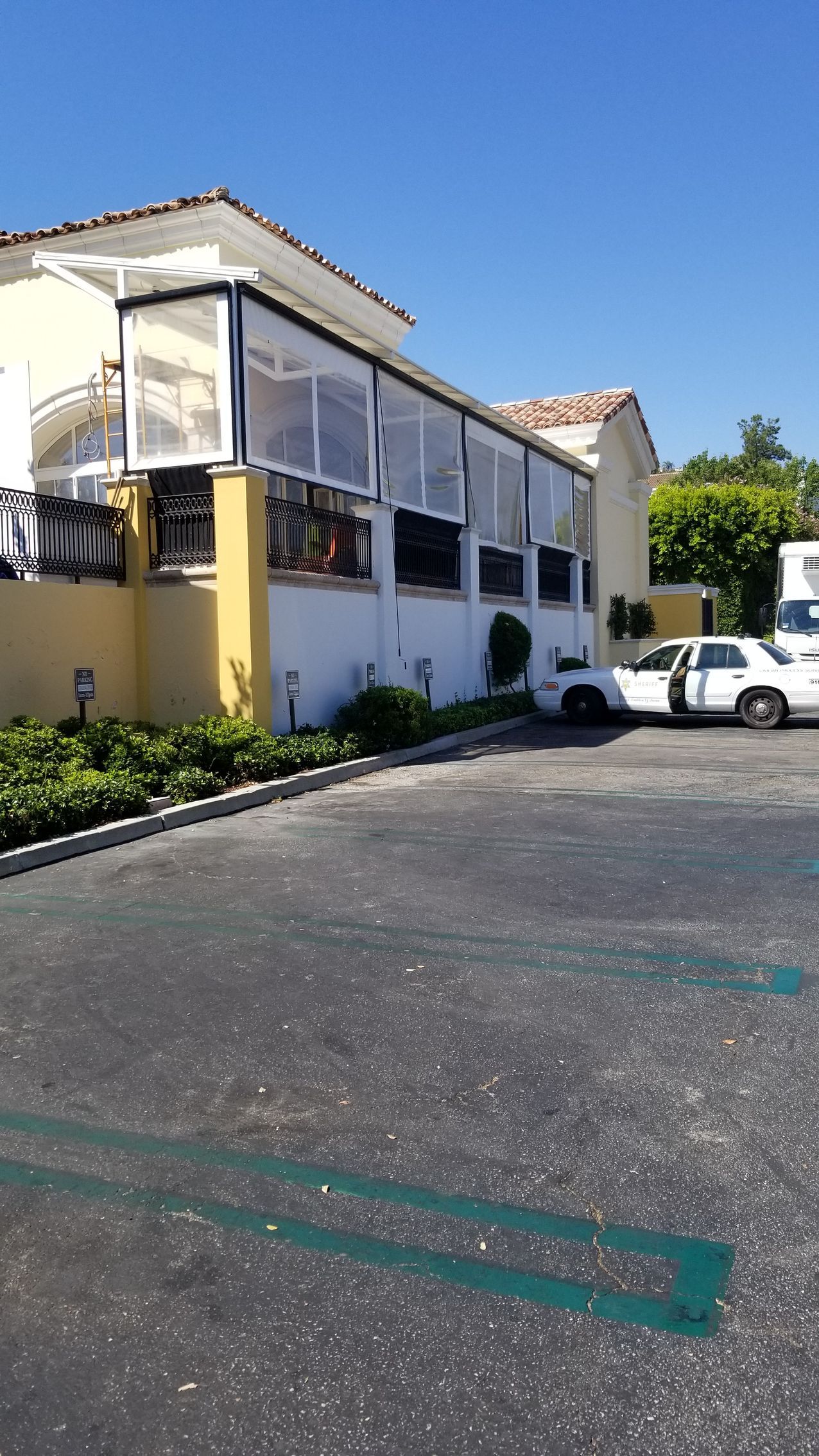 Two-story cream building with screened porch beside a parking lot, with a white pickup truck nearby.