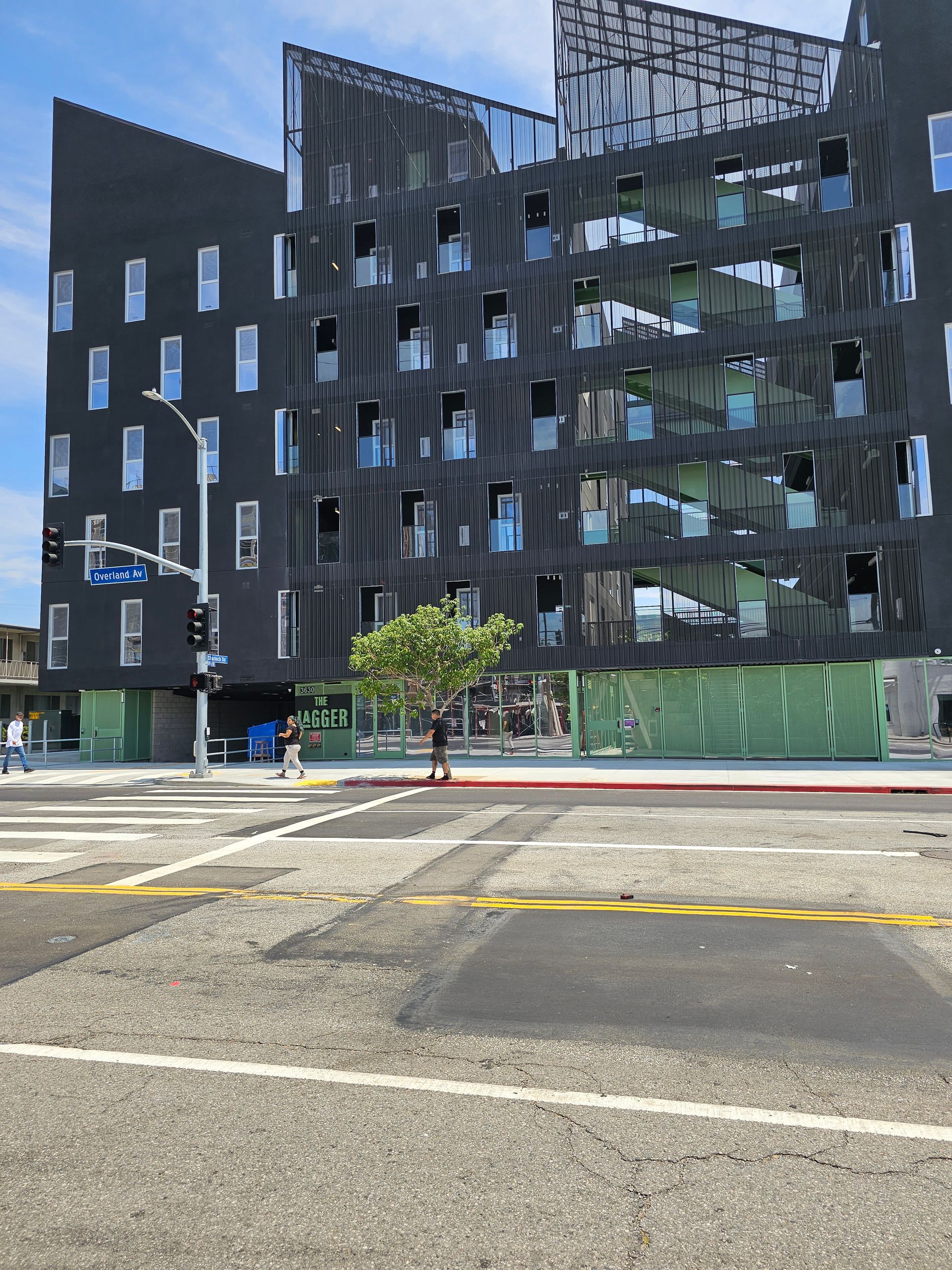Modern black apartment buildings behind a street and crosswalk under clear daylight