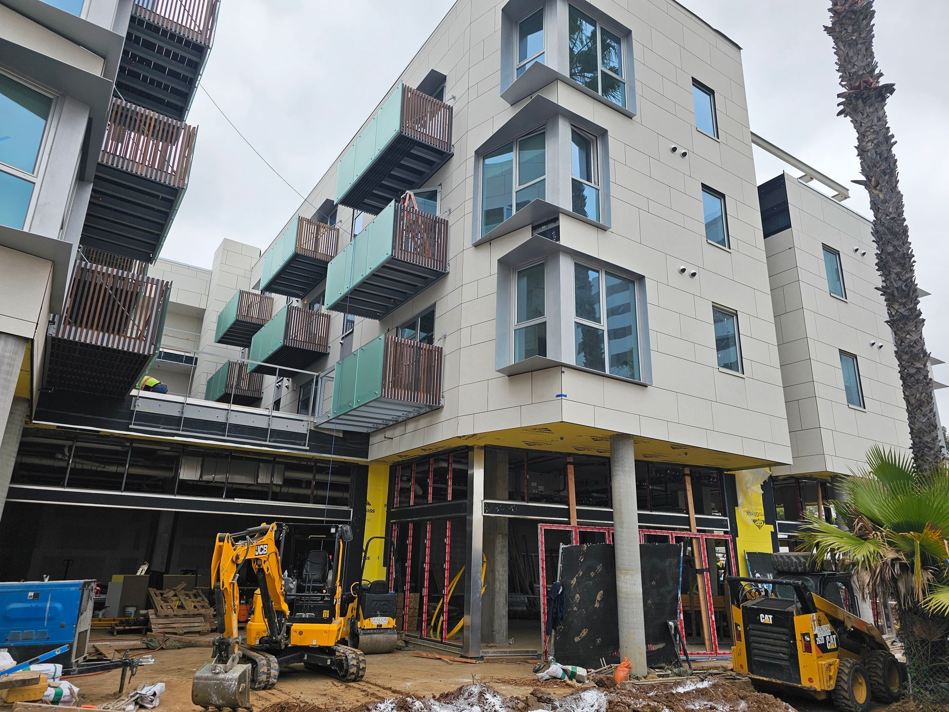 Modern apartment building under construction with excavators and scaffolding outside