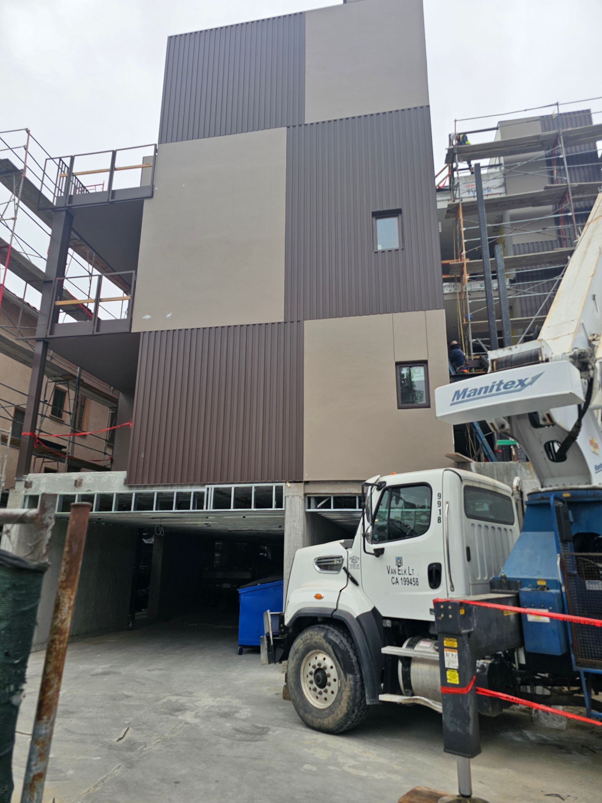 Construction site with a modern building facade and a white utility truck in front