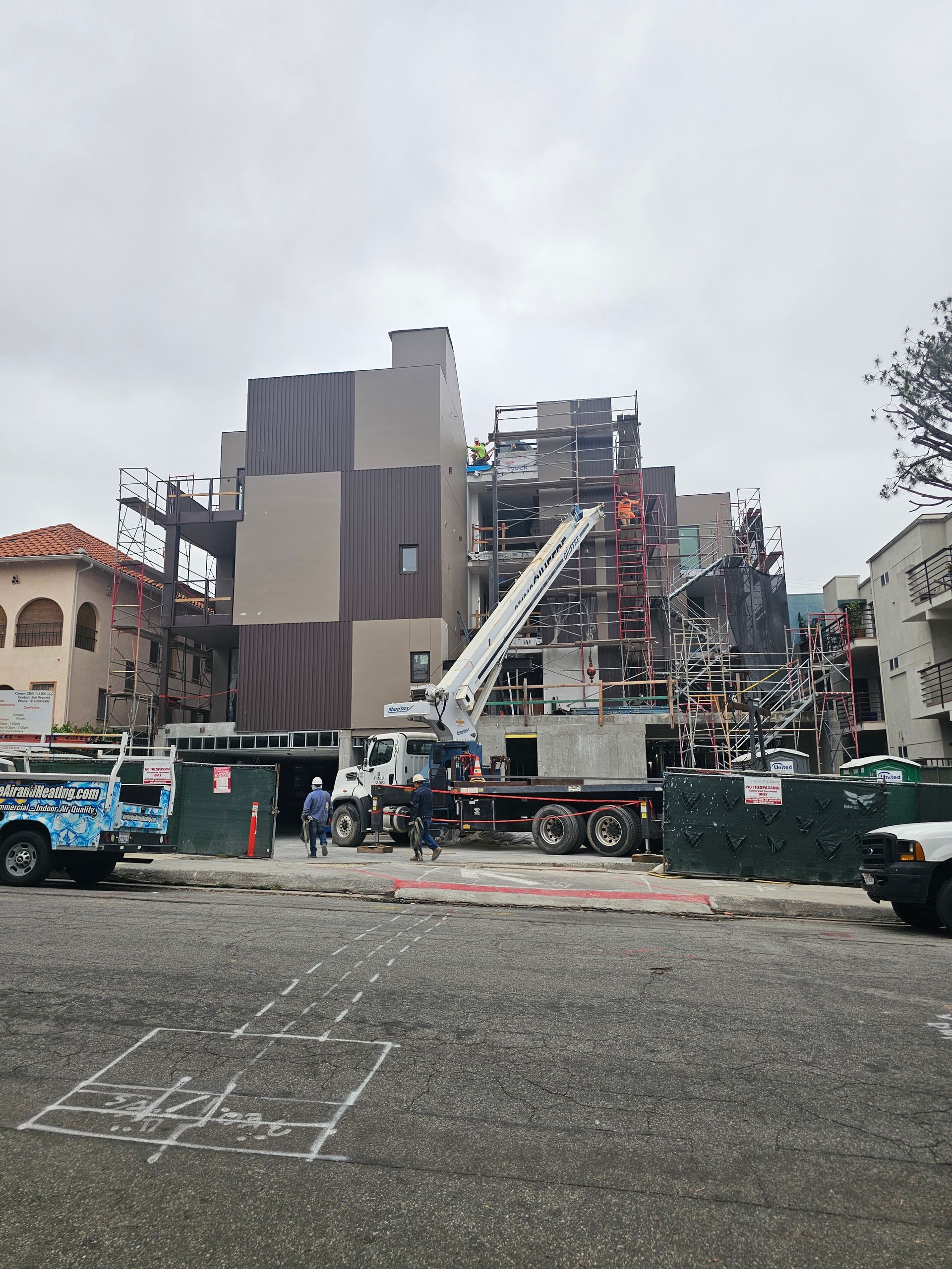 Construction site with a large industrial machine, trucks, and workers behind a fenced area.
