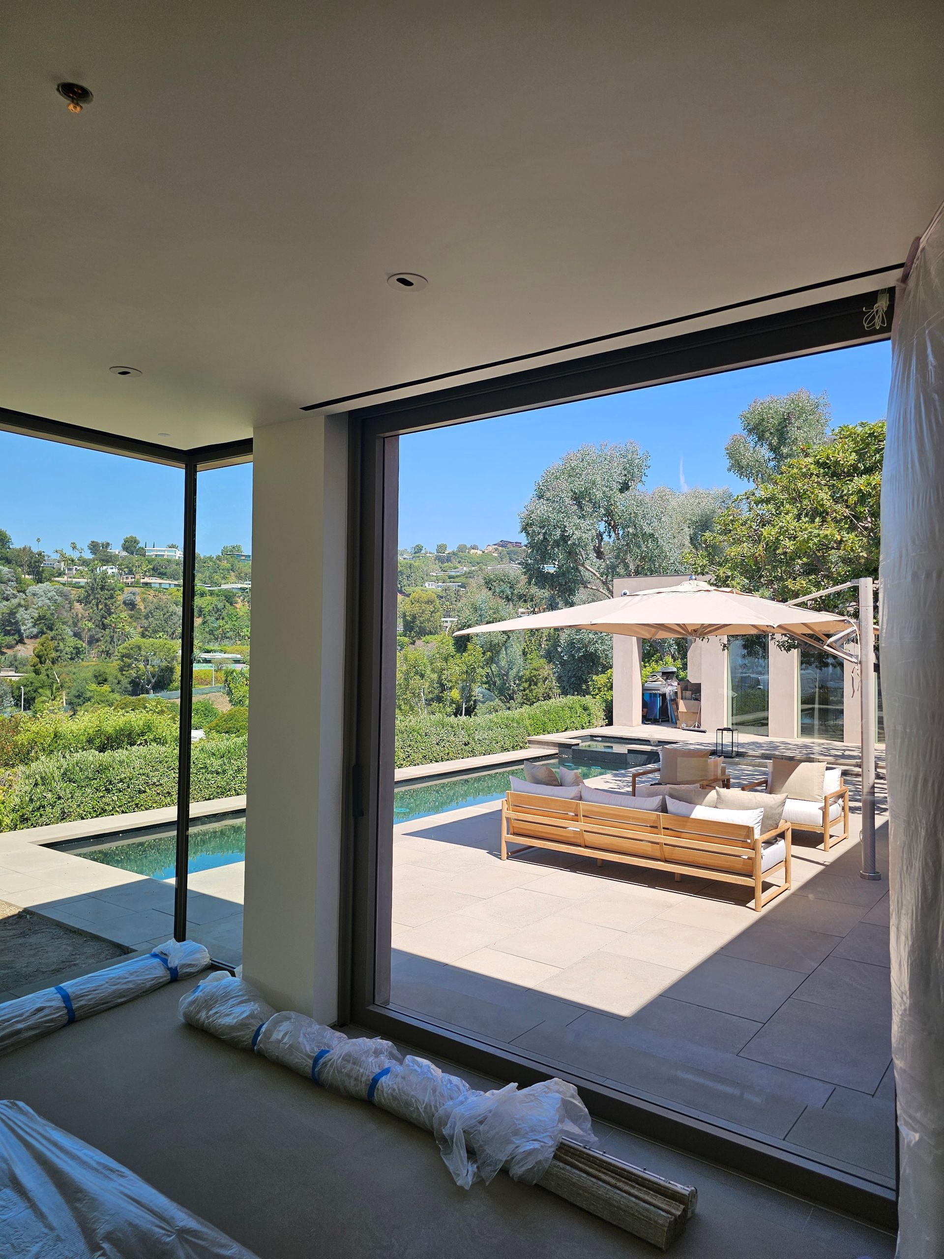 Modern patio with lounge seating, pool, and mountain view through large sliding glass doors