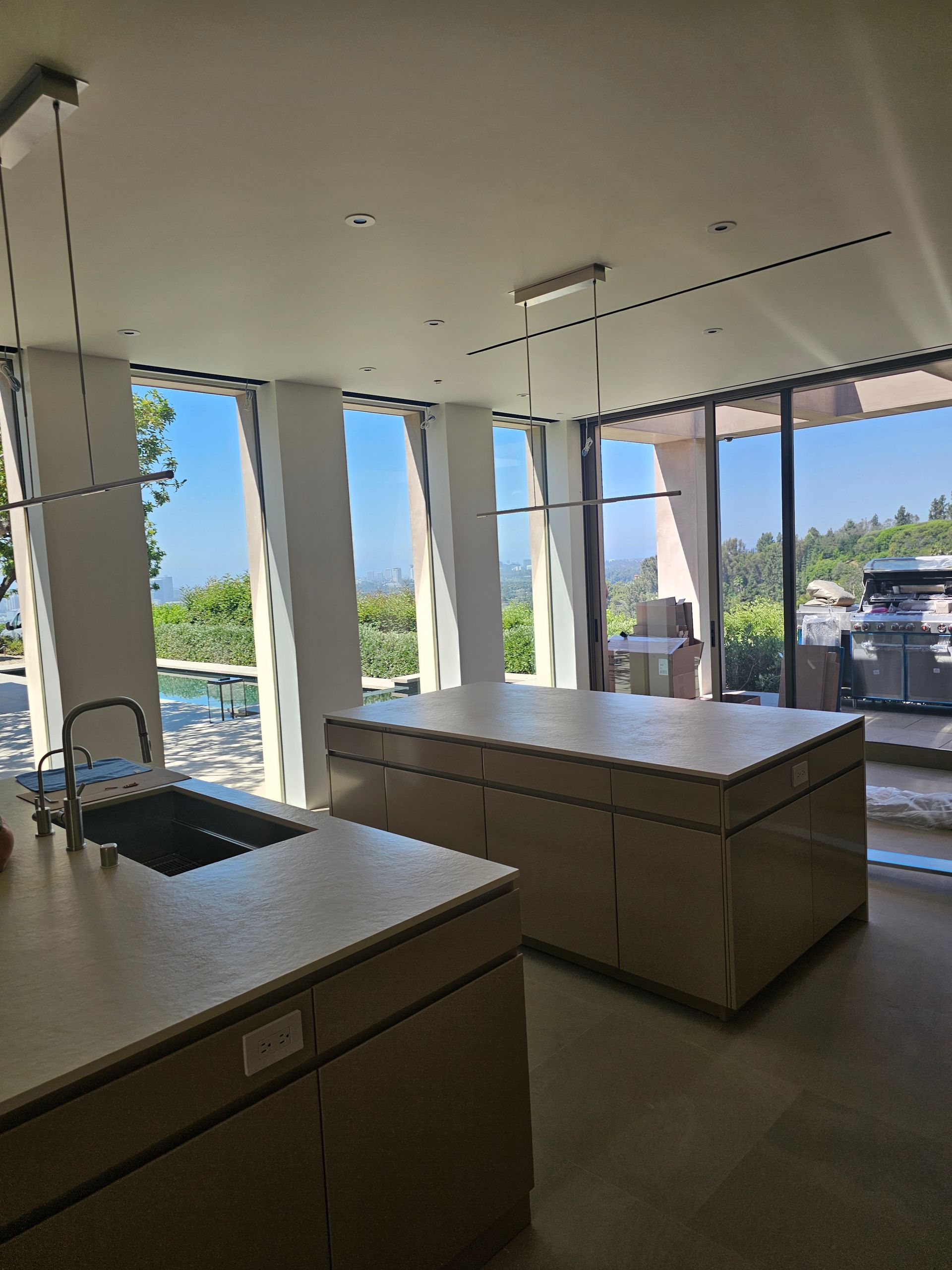 Modern kitchen with island and large windows overlooking a sunny patio and pool