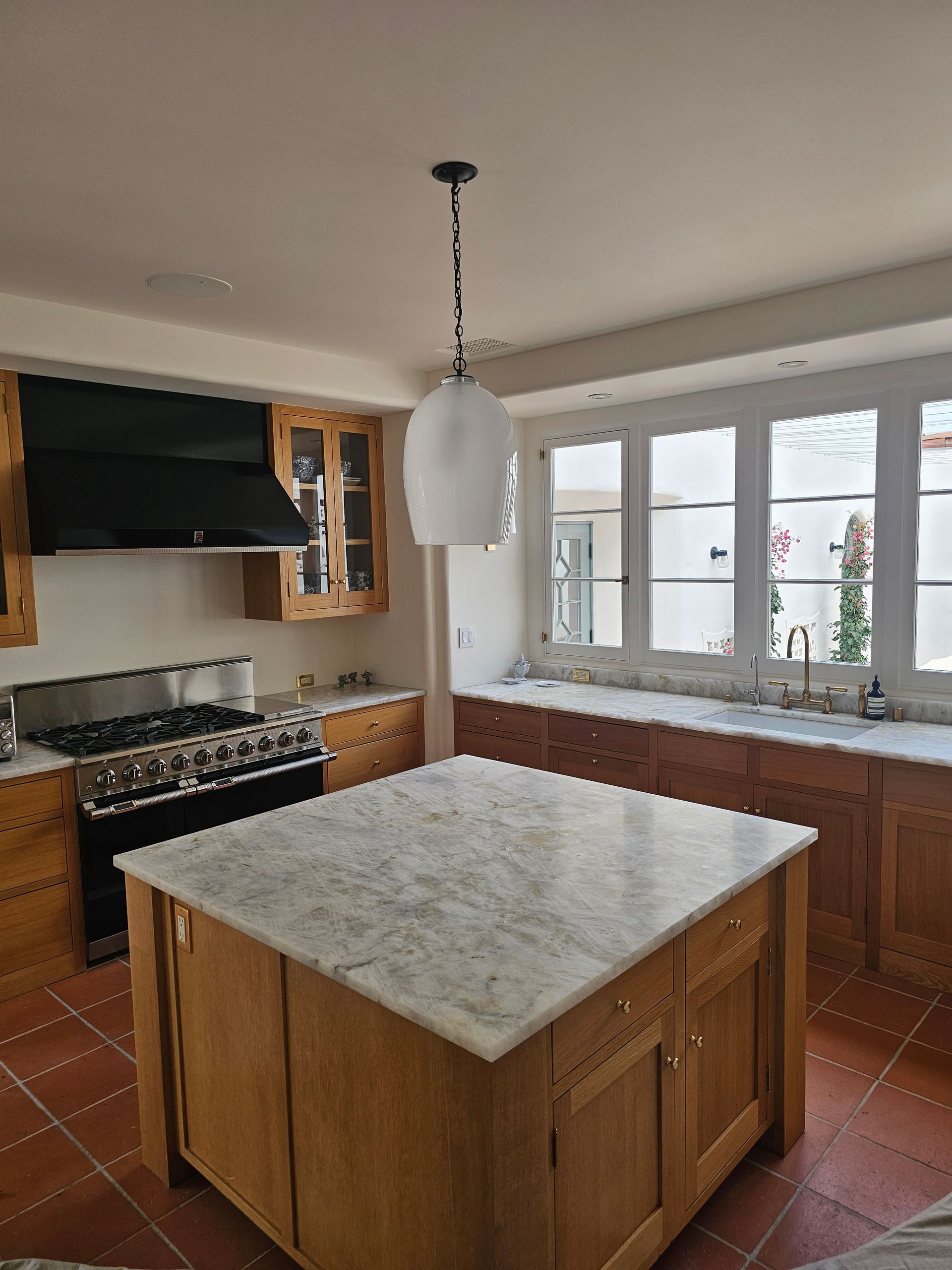 Bright kitchen with a central island, stove, wood cabinets, and windows along the right wall.