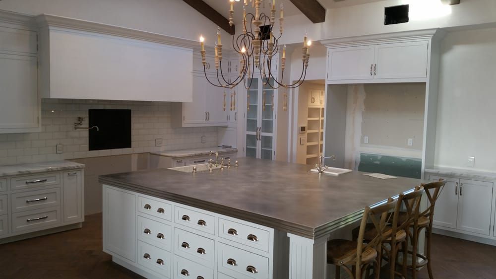 Bright white kitchen with a large island, chandelier, built-in cabinets, and wood flooring