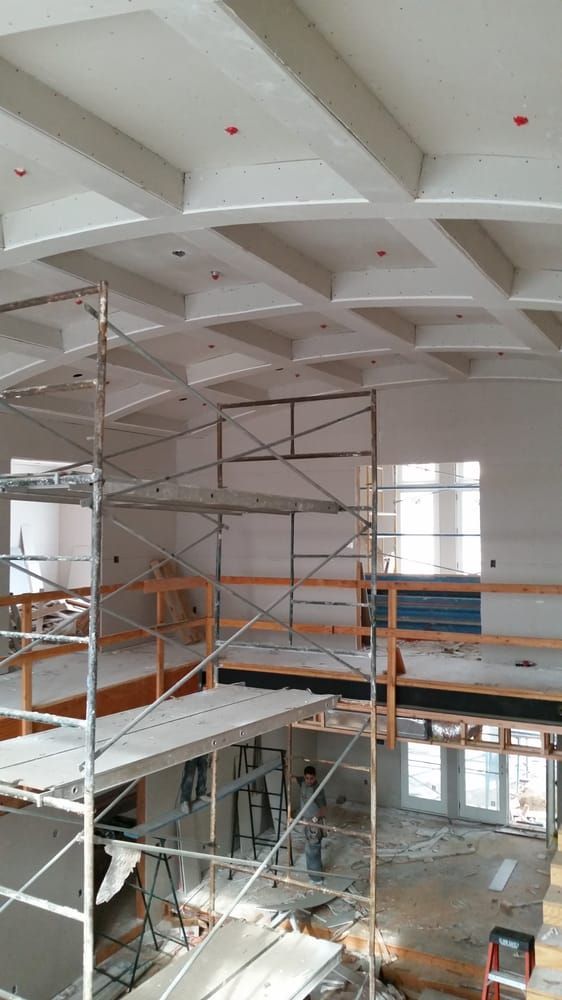 Scaffolding in a construction site with white ceiling beams and orange safety rails.