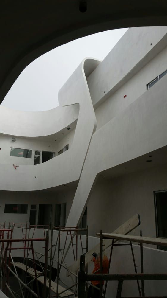 Modern white building courtyard with curved walls and scaffolding in front