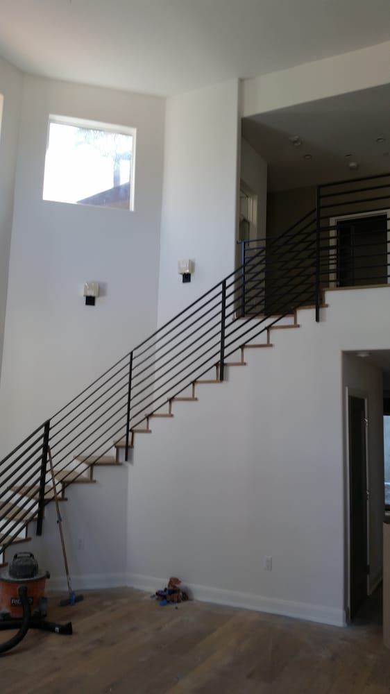 Interior staircase with black railing in a bright white room and wood floor