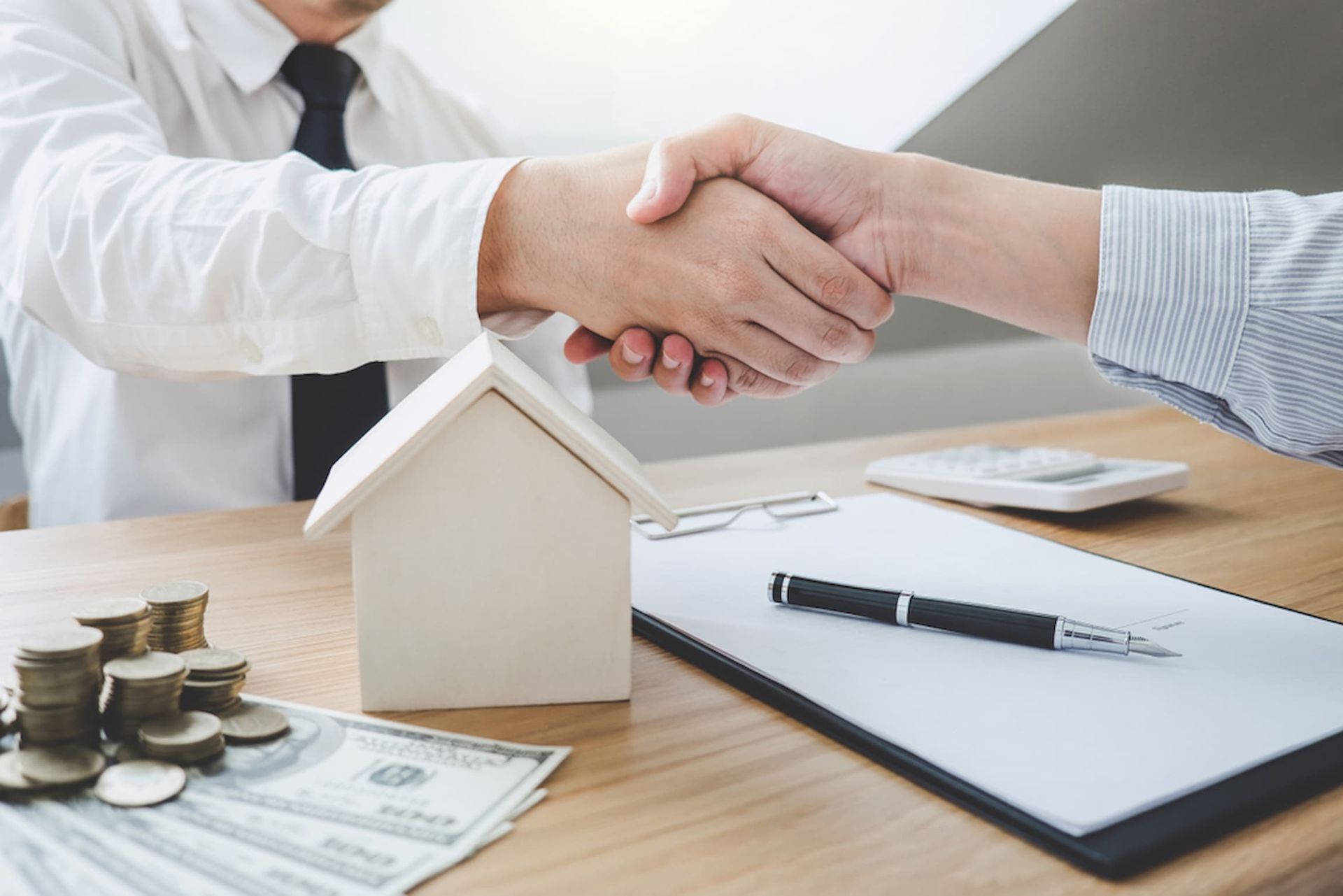 A Man Is Shaking Hands with Another Man While Sitting at A Table — Cairns Property Collective in Edmonton, QLD