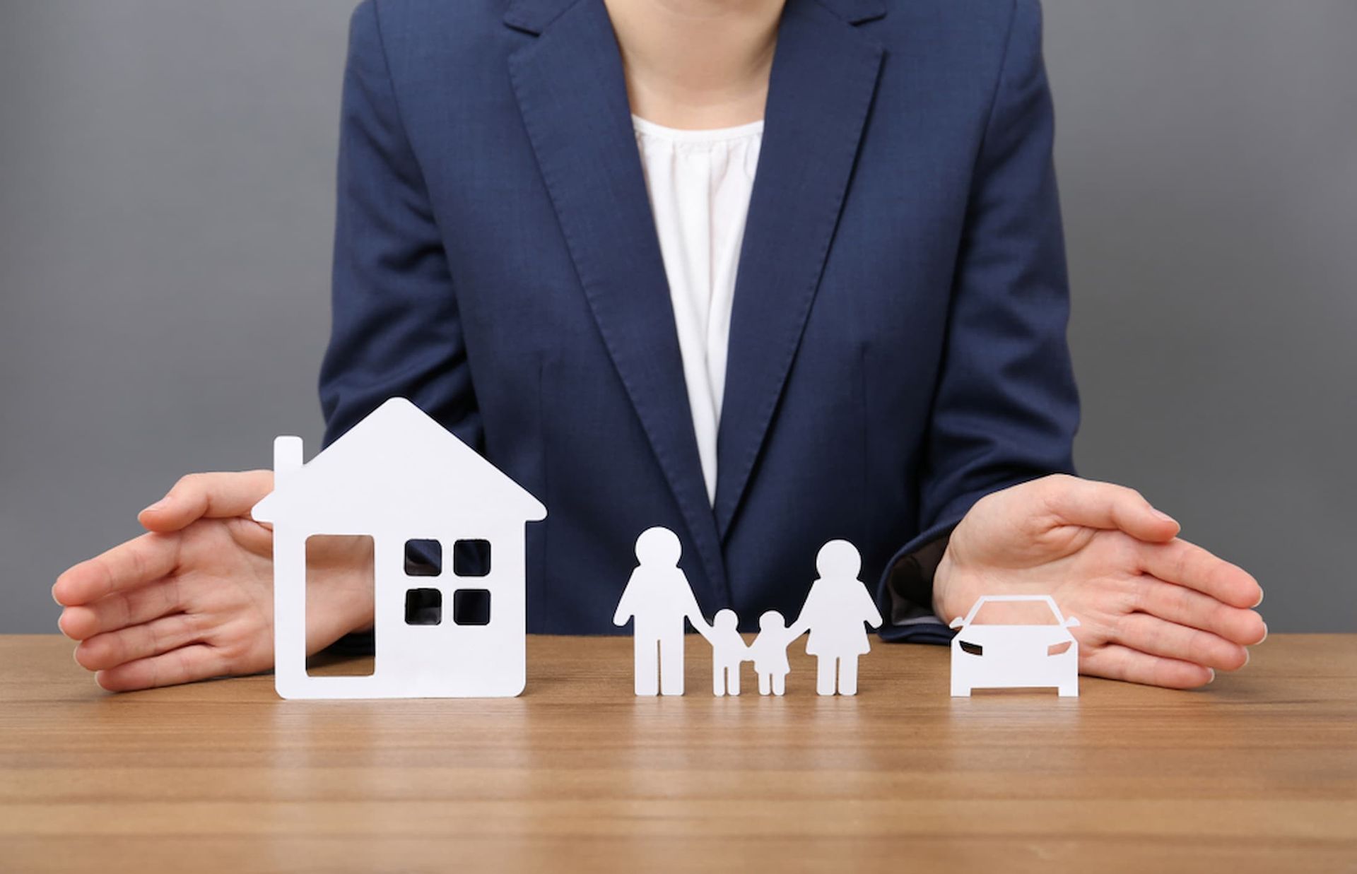 A Woman Is Sitting at A Table with House, Family, and Car Cut out Of Paper — Cairns Property Collective in Trinity Park, QLD