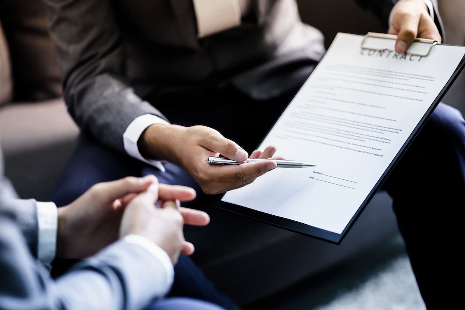 Two People Are Sitting on A Couch Looking at A Clipboard with A Pen — Cairns Property Collective in Trinity Park, QLD