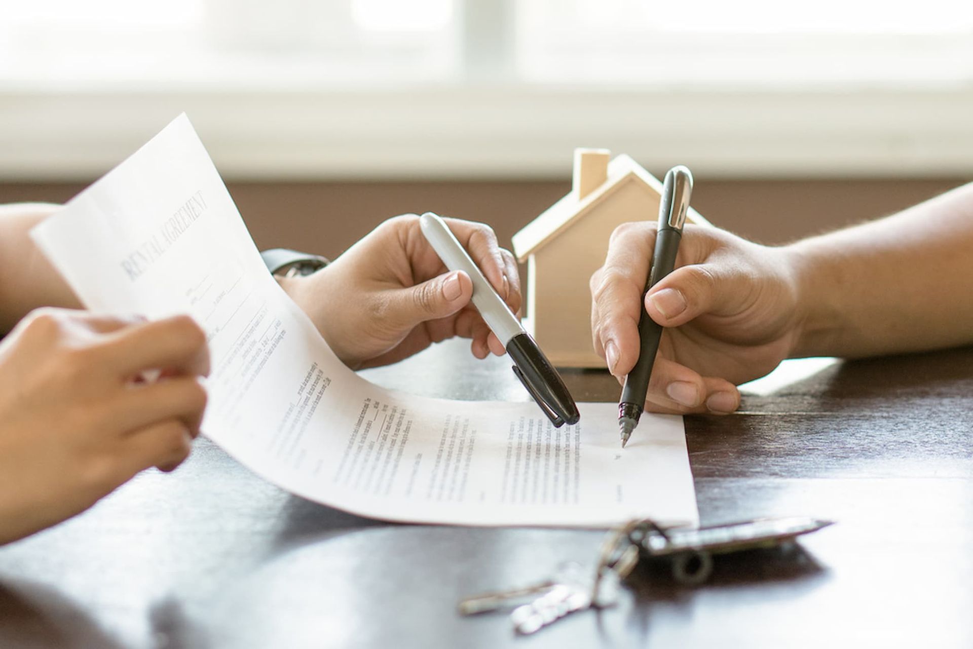 A Couple of People Are Sitting at A Table Signing a Document — Cairns Property Collective in Trinity Park, QLD