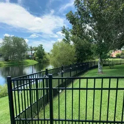 Black aluminum fence enclosing a yard while preserving an open pond view