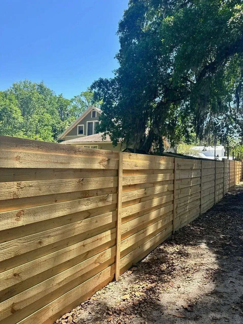 Horizontal wood fence built with horizontal boards along a residential property