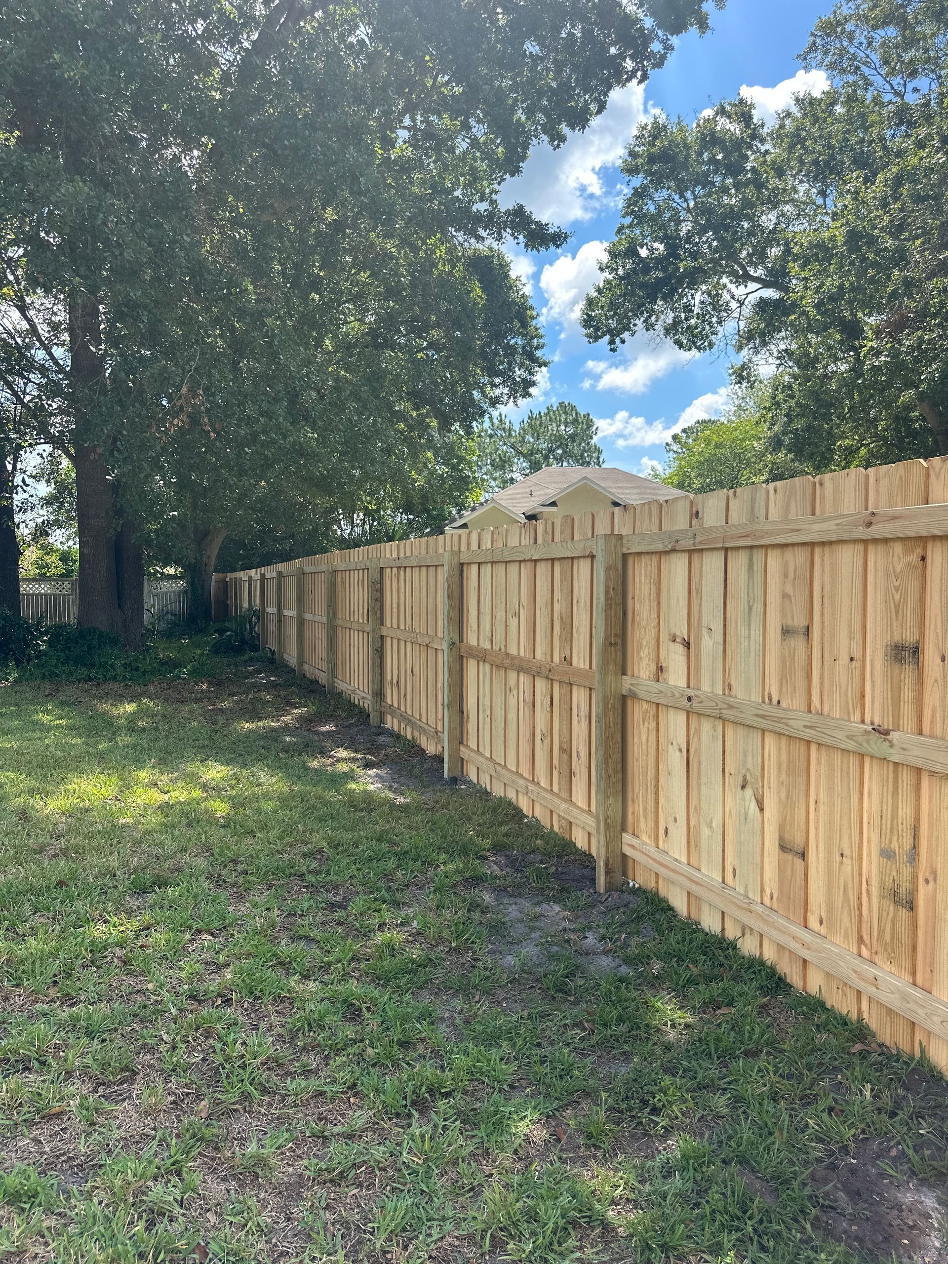 Wooden privacy fence against a blue sky with clouds