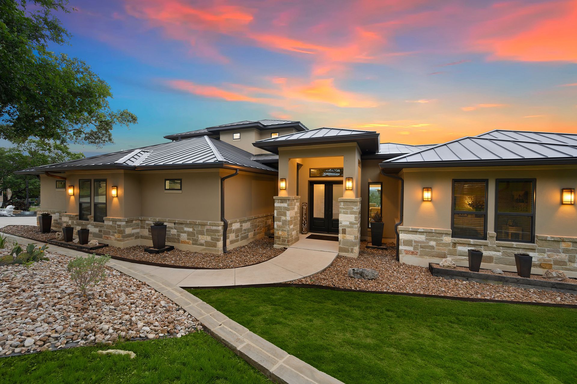A large house with a walkway leading to it and a sunset in the background.