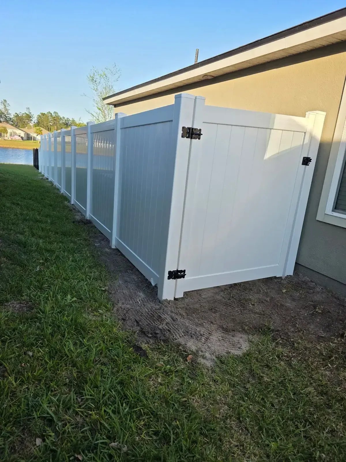 White vinyl privacy fence with a double gate for equipment access