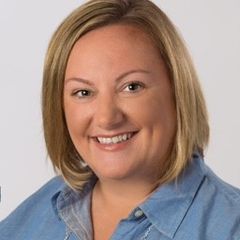 A woman in a blue shirt is smiling for the camera.