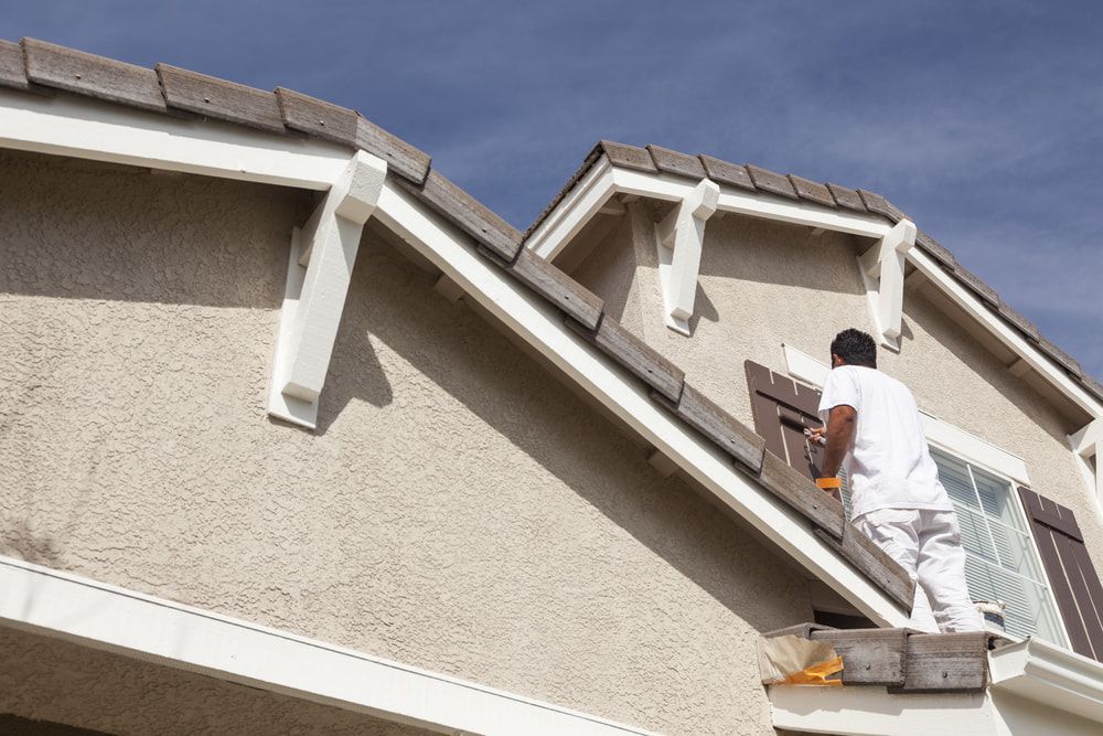 Man Painting a House Exterior, Standing on Scaffolding — BK Painting & Property Maintenance in Emerald, QLD