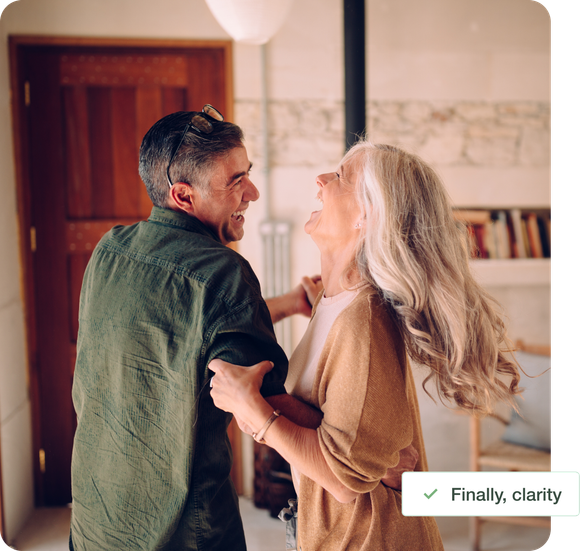 Smiling couple dancing in a warmly lit living room, holding hands and facing each other