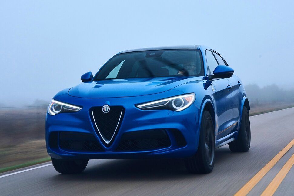 A blue car is driving down a foggy road.
