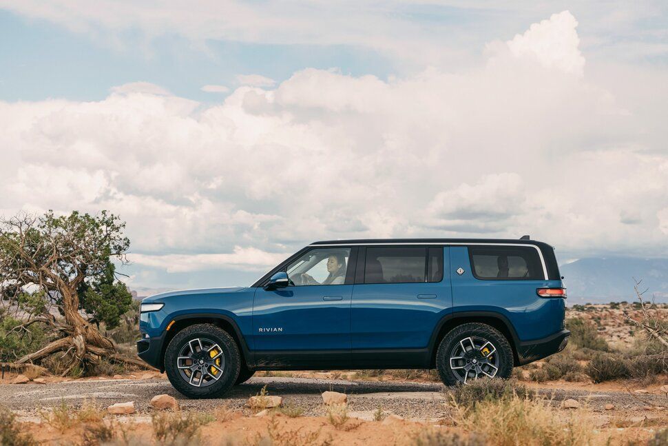 A blue suv is parked on the side of a dirt road in the desert.