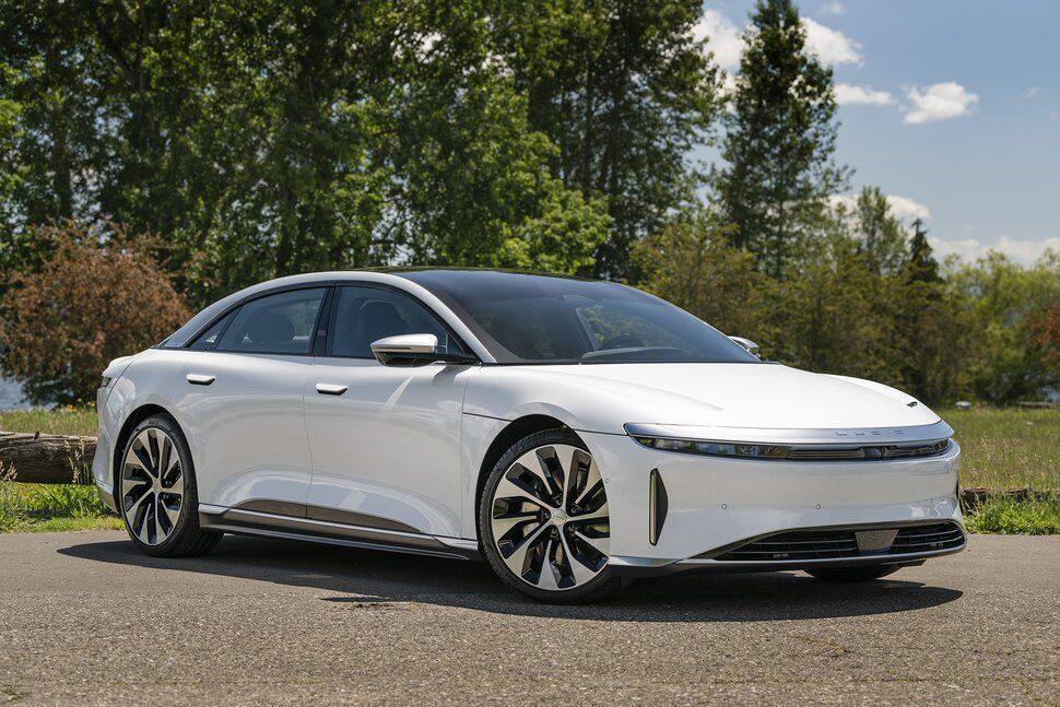A white electric car is parked on the side of the road.