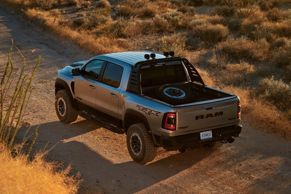 A ram truck is driving down a dirt road in the desert.