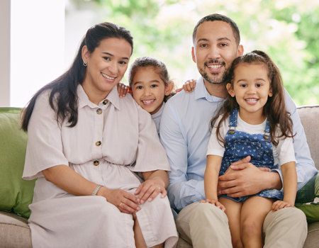 A family is sitting on a couch posing for a picture.