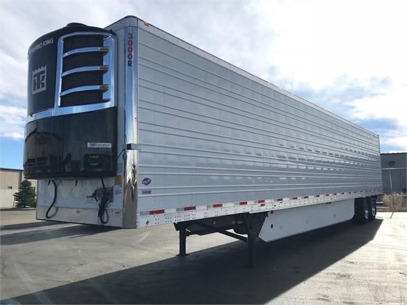 A white refrigerated trailer is parked in a parking lot.