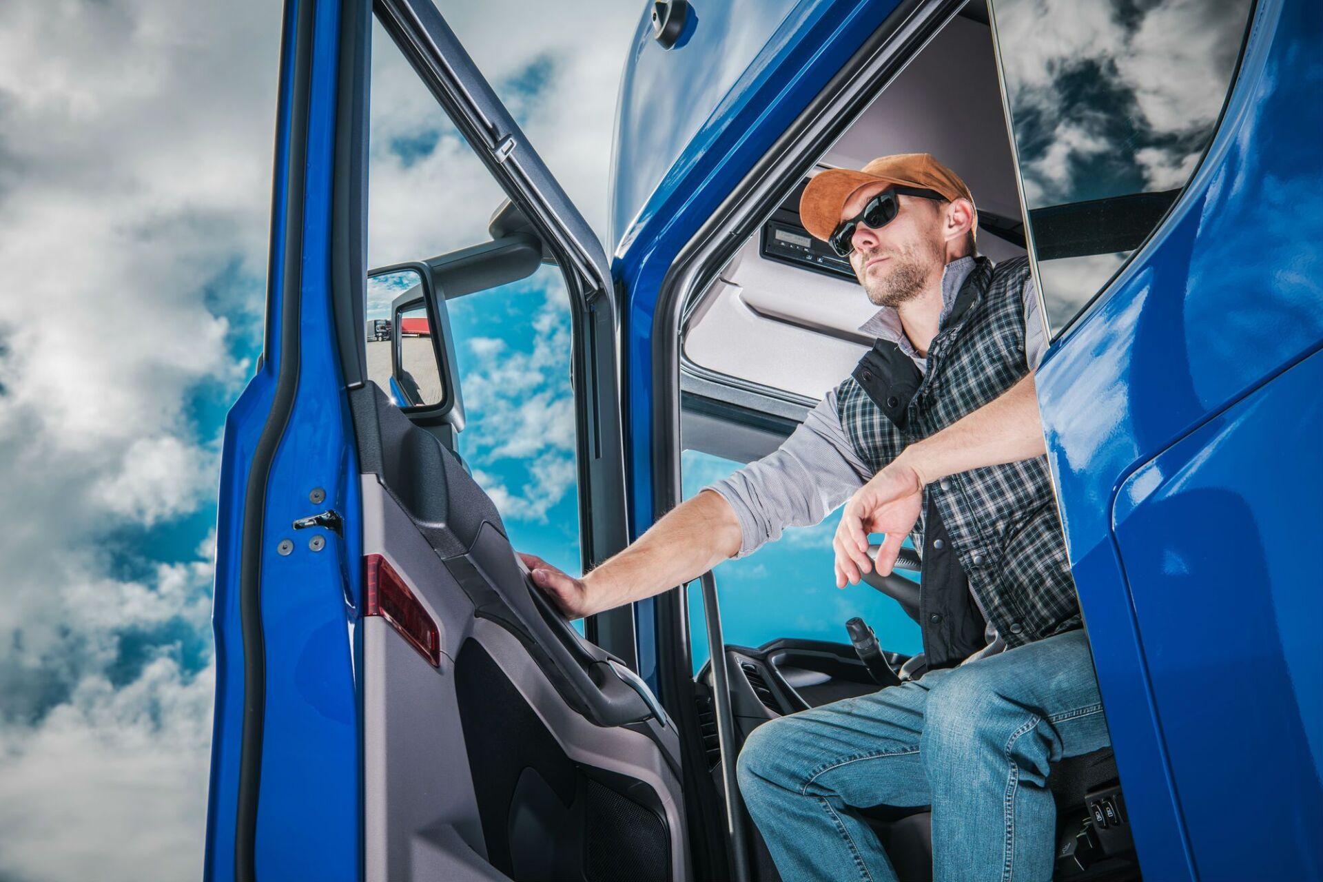 A man is sitting in the driver 's seat of a blue truck.