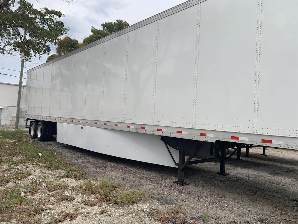 A white semi trailer is parked on the side of the road.