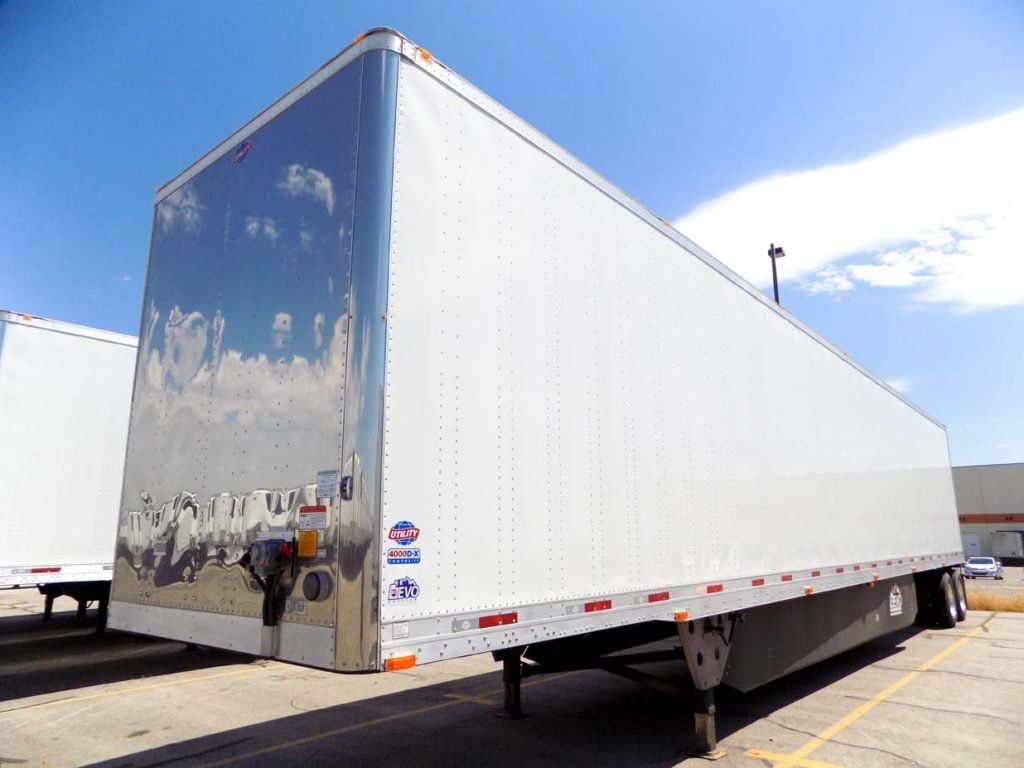 A large white trailer is parked in a parking lot.