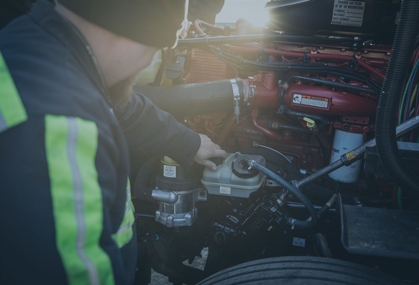 A man is working on the engine of a semi truck.