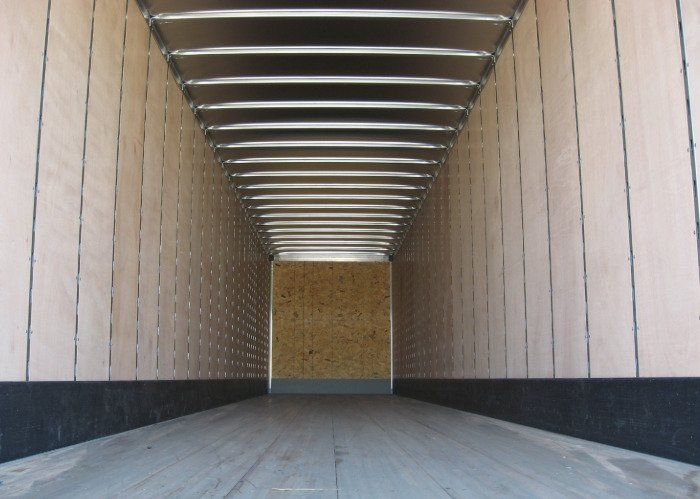 The inside of an empty trailer with a wooden floor