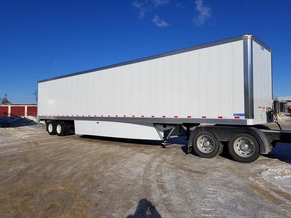 A white semi trailer is parked in a snowy parking lot.
