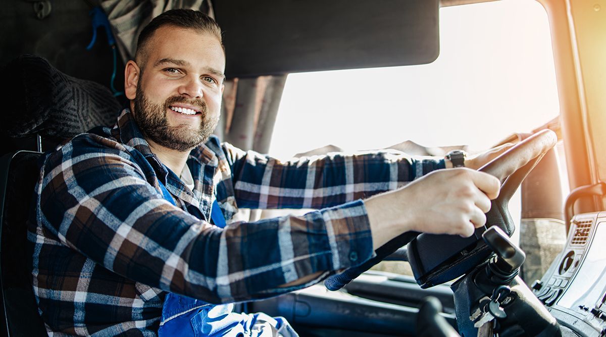 A man is sitting in the driver 's seat of a truck.