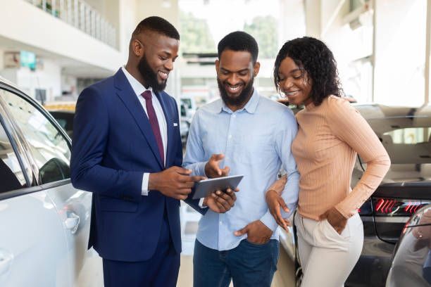 A man and a woman are looking at a tablet in a car showroom.
