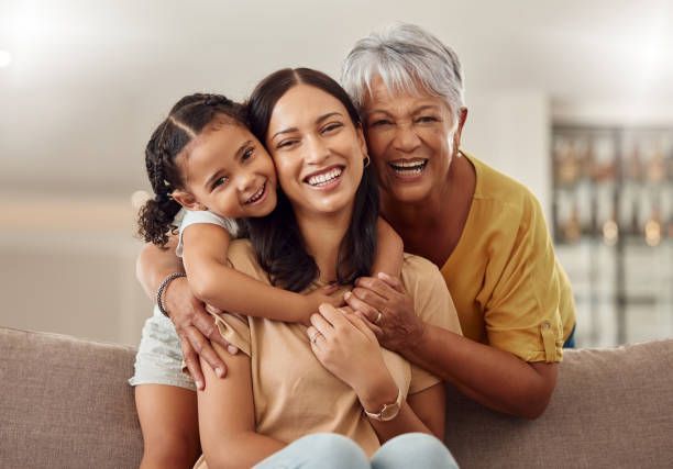 Three women are sitting on a couch hugging each other.