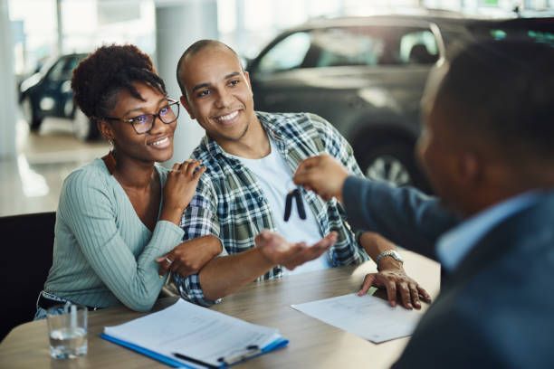A man is giving a car key to a couple sitting at a table.